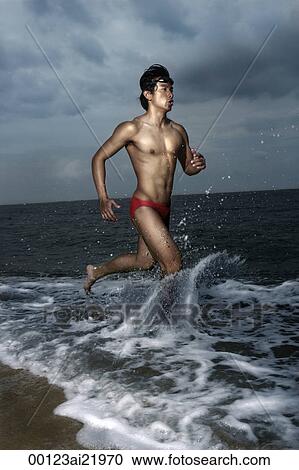 Muscled man wearing swim trunks, running along ocean View Large Photo Image Stock Image - Muscled man wearing swim trunks, running along ocean. Fotosearch