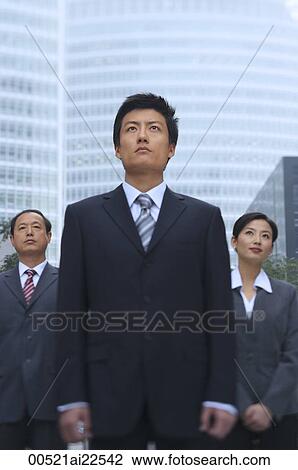 Stock Image - Three business professionals stand in front of a skyscraper. Fotosearch