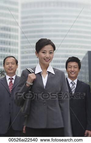 Stock Image - Three business professionals stand in front of a skyscraper. Fotosearch