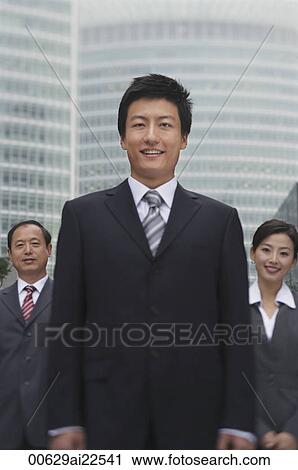 Stock Image - Three business professionals stand in front of a skyscraper. Fotosearch