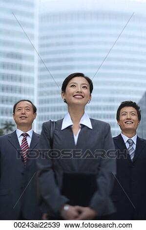 Three business professionals stand in front of a skyscraper View Large Photo Image Stock Photo - Three business professionals stand in front of a skyscraper. Fotosearch