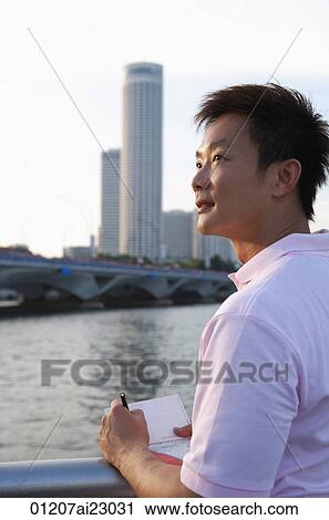 Stock Image - Tourist with pen and paper looking into distance. Fotosearch