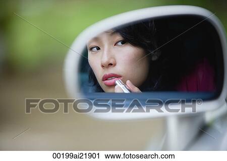 Woman applying lipstick in side view mirror of car View Large Photo Image Stock Image - Woman applying lipstick in side view mirror of car. Fotosearch