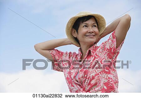 Stock Image - Woman at the beach, looking into distance. Fotosearch
