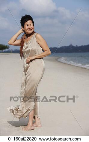 Stock Image - Woman at the beach, looking into distance. Fotosearch