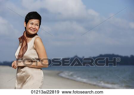 Stock Photo - Woman at the beach, looking into distance. Fotosearch