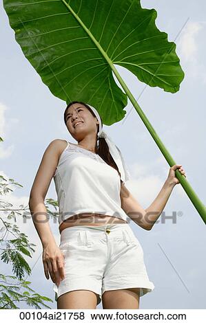 Stock Photo - Woman holding onto large leaf. Fotosearch