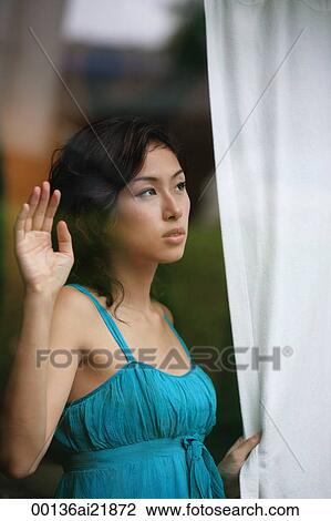 Woman looking through window, holding curtain View Large Photo Image Stock Image - Woman looking through window, holding curtain. Fotosearch