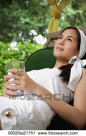 Woman lounging on chair outside, drinking water View Large Photo Image Stock Image - Woman lounging on chair outside, drinking water. Fotosearch