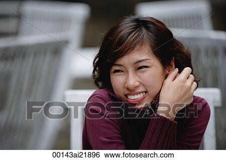 Stock Photograph - woman sitting at an outdoor cafe, wearing sweater, smiling. Fotosearch