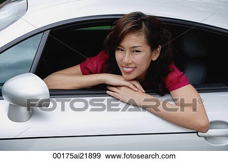 Woman sitting in car, hanging out driver side window, smiling at camera View Large Photo Image Stock Photo - Woman sitting in car, hanging out driver side window, smiling at camera. Fotosearch