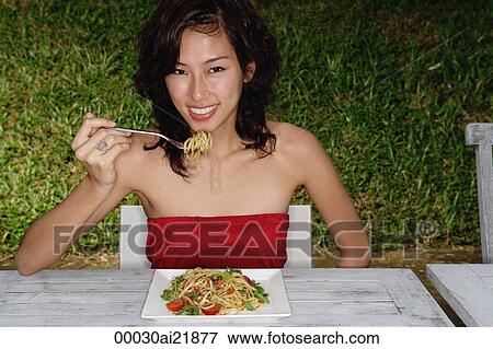 Woman sitting in restaurant eating pasta, looking at camera, smiling View Large Photo Image Stock Photo - Woman sitting in restaurant eating pasta, looking at camera, smiling. Fotosearch