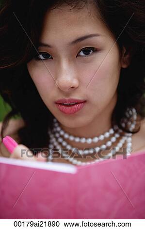Woman wearing necklace and writing in pink journal, looking at camera View Large Photo Image Stock Image - Woman wearing necklace and writing in pink journal, looking at camera. Fotosearch