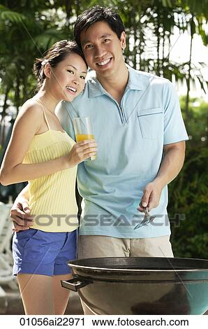 Stock Image - Young couple enjoying a barbeque. Fotosearch