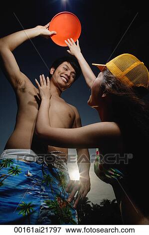 Stock Photo - Young couple in bathing suits playing Frisbee. Fotosearch