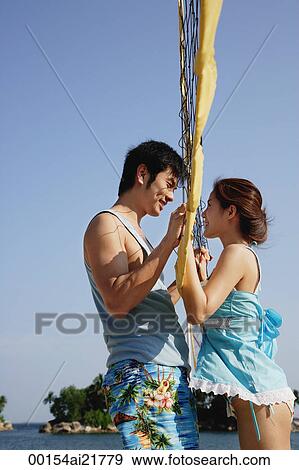Stock Photo - Young couple on beach meeting by volleyball net. Fotosearch