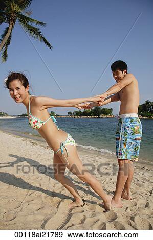Young couple on beach playing and holding hands View Large Photo Image Stock Photo - Young couple on beach playing and holding hands. Fotosearch