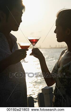 Young couple on beach toasting with martini's View Large Photo Image Stock Image - Young couple on beach toasting with martini's. Fotosearch