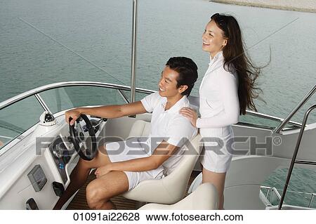 Stock Photo - Young couple on yacht, looking into distance. Fotosearch
