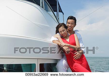 Stock Photo - Young couple on yacht, smiling at camera. Fotosearch