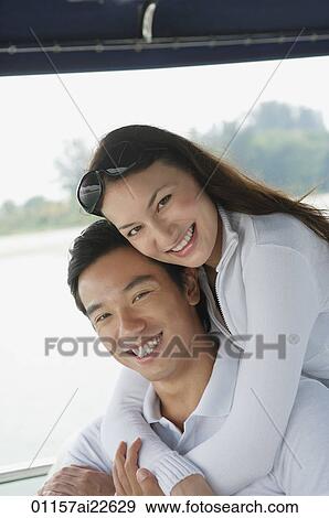 Stock Photo - Young couple on yacht, smiling at camera. Fotosearch