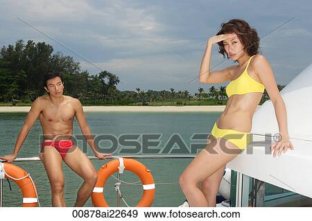 Stock Photo - Young couple on yacht, woman looking at camera. Fotosearch