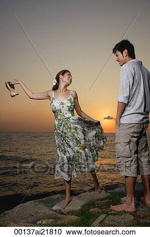 Young couple standing on rocks overlooking ocean View Large Photo Image Stock Image - Young couple standing on rocks overlooking ocean. Fotosearch