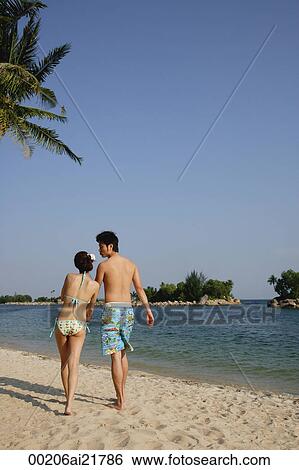 Young couple walking on beach, back to camera View Large Photo Image Stock Photograph - Young couple walking on beach, back to camera. Fotosearch