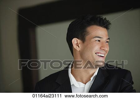 Stock Image - Young man laughing while looking sideways. Fotosearch