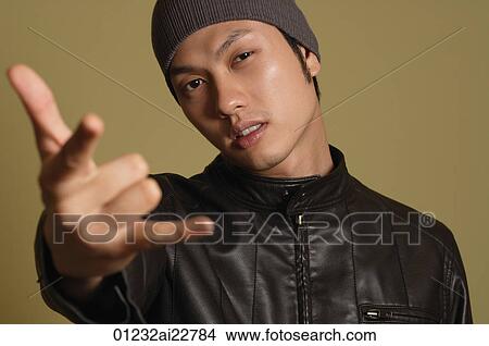 Picture - Young man looking at camera, making hand gesture. Fotosearch