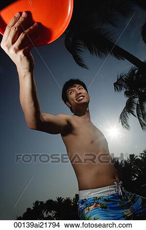 Picture - Young man on beach throwing Frisbee. Fotosearch