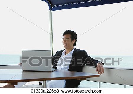 Young man on yacht, using laptop View Large Photo Image Stock Photo - Young man on yacht, using laptop. Fotosearch