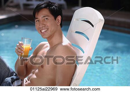 Stock Photo - Young man relaxing in deck chair by the pool. Fotosearch