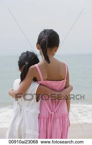 Young sisters hugging and looking out at sea View Large Photo Image Stock Photo - Young sisters hugging and looking out at sea. Fotosearch