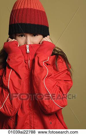 Stock Photo - Young woman covering face and looking at camera. Fotosearch