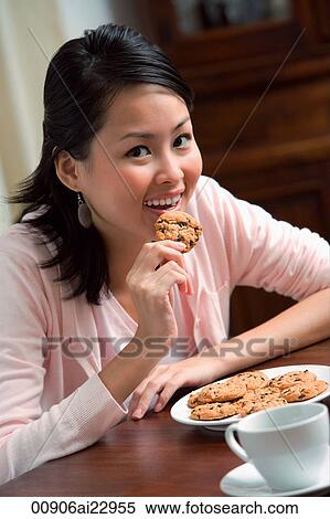 Stock Photography - Young woman eating cookie. Fotosearch