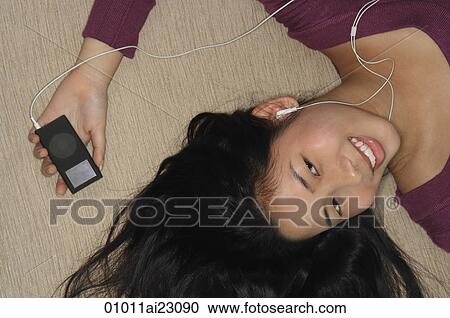 Stock Image - Young woman listening to music. Fotosearch