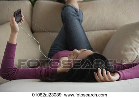 Stock Photo - Young woman listening to music. Fotosearch