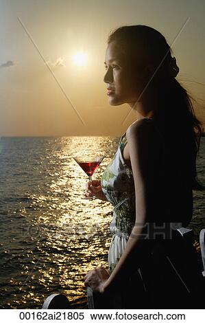 Young woman looking out over the ocean at sunset View Large Photo Image Stock Photography - Young woman looking out over the ocean at sunset. Fotosearch