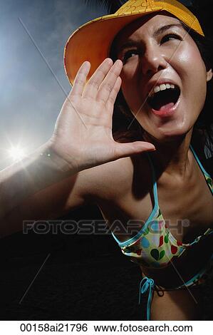 Young woman on beach in bikini yelling and screaming towards camera View Large Photo Image Stock Photograph - Young woman on beach in bikini yelling and screaming towards camera. Fotosearch