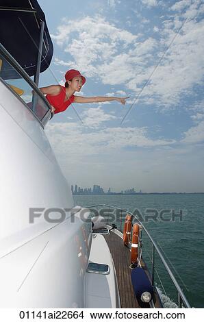 Young woman on yacht, pointing into distance View Large Photo Image Picture - Young woman on yacht, pointing into distance. Fotosearch