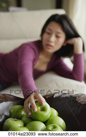 Young woman reaching for apple View Large Photo Image Stock Image - Young woman reaching for apple. Fotosearch