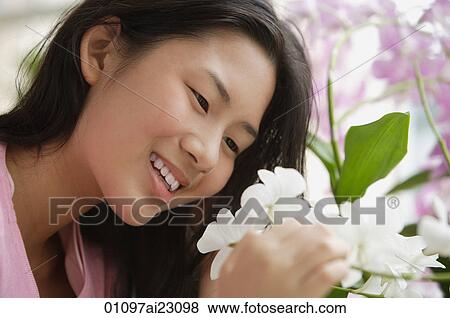 Young woman smiling at flower View Large Photo Image Stock Photo - Young woman smiling at flower. Fotosearch