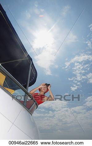 Stock Photography - Young woman with binoculars on yacht, looking into distance. Fotosearch