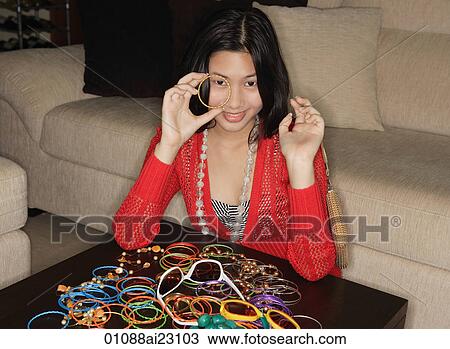 Stock Image - Young woman with many bracelets on table. Fotosearch