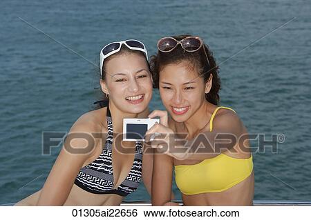Stock Photograph - Young women taking pictures of themselves. Fotosearch