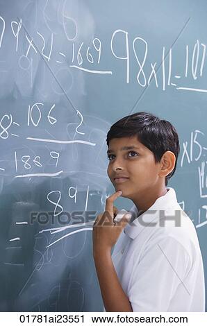 Stock Image - boy at chalkboard, finger on chin. Fotosearch
