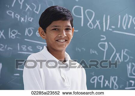 Stock Image - boy in front of chalkboard smiling. Fotosearch