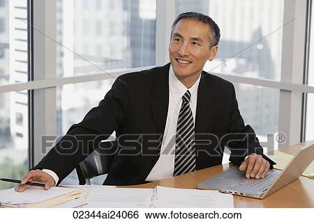 Stock Photograph - businessman at table with laptop. Fotosearch