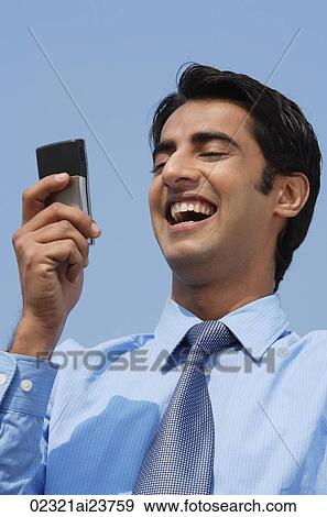 Stock Photo - businessman reading message, laughing. Fotosearch